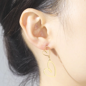 Minimalist double heart dangle earrings in gold finish worn by a model for a stylish look