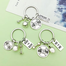 Close-up of silver fitness keychains featuring kettlebell, barbell, and dumbbell charms