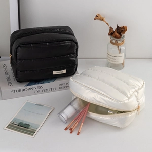 Quilted cosmetic bags showing storage capacity with makeup brushes and bottles