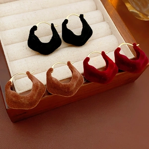 Detail of flocking irregular round earrings in black, brown and red on a jewelry tray
