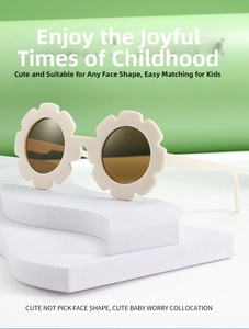Detail of cream flower-shaped kids sunglasses with dark brown round lenses on a green base