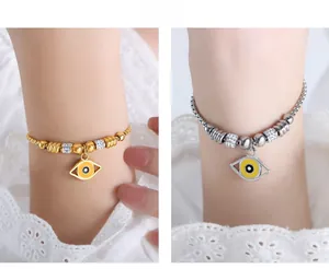 Macro view of gold and silver devil eye pendants on elegant stainless steel bracelets