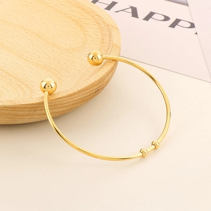 Minimalist 18K gold-plated C-shaped stainless steel open cuff bracelet on a wooden tray