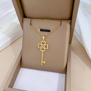 Close-up of golden clover key pendant with sparkling pavé crystals in a jewelry box