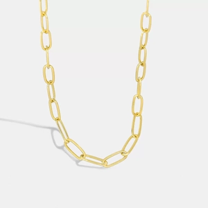 Macro close-up of golden paperclip chain necklace with textured metal links and natural shadow