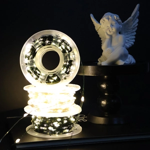Close-up of LED copper wire fairy lights on spools with a decorative angel statue