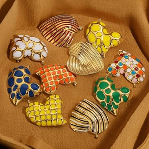 Enamel heart charms in leopard and striped patterns on soft brown fabric background