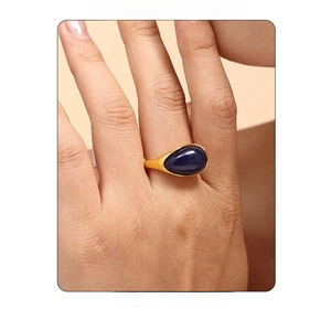 Macro shot of a gold-plated ring with large blue resin stone on a hand close-up