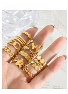 Close-up of stacked gold rings featuring floral, heart and chain designs for women