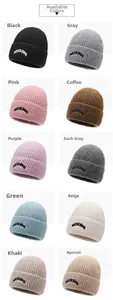 Detail showing ten colorful cuffed beanies in thick ribbed knit with letter embroidery
