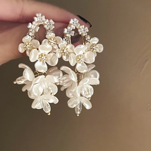 Close-up of pearl shell flower earrings with shimmering rhinestones and gold details