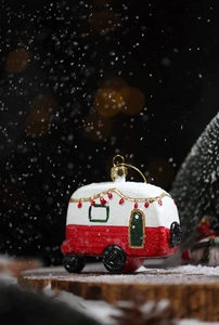 Close-up of a red and white RV Christmas ornament with frosted snow texture on wood