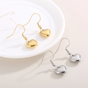 Vue détaillée de boucles d'oreilles cœur en or et argent sur un plat décoratif