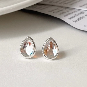 Close-up of minimalist silver water drop earrings with AB crystals on a paper background