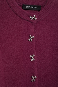 Close-up of silver bow buttons and plush knit texture on a berry red cardigan jacket