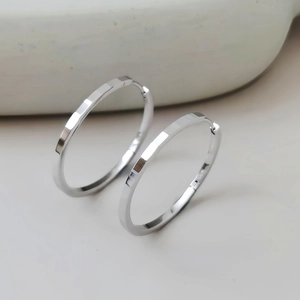 Detail shot of S925 silver hoop earrings with geometric faceted texture and glossy finish