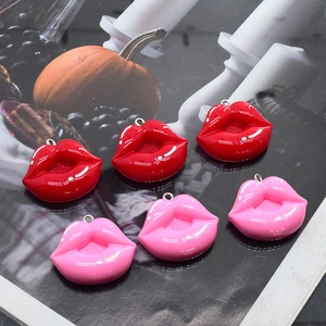 Colgantes de labios de resina rojos y rosas para bisutería DIY sobre fondo de revista