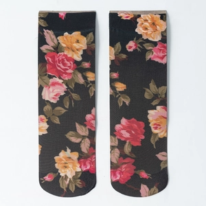 Detailed view of floral socks with red roses and green leaves on black fabric