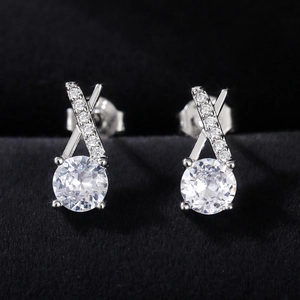 Macro shot of silver flower earrings with X-shaped zircon setting on black velvet