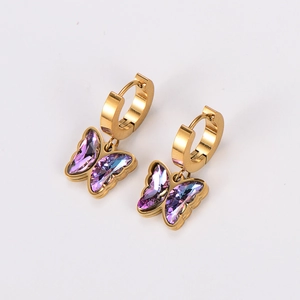 Detail view of gold hoop earrings with purple crystal butterfly pendants on white background