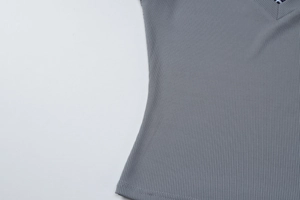 Détail de la texture en maille côtelée grise et de l'ourlet sur un haut polo femme