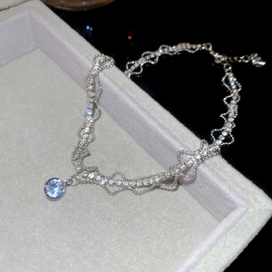 Close-up of sparkling zircon geometric pendant on silver layered wavy necklace chain