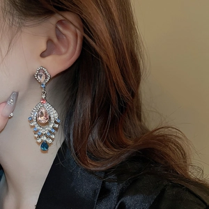 Close-up of vintage fan-shaped drop earrings with pink stones and diamonds on model