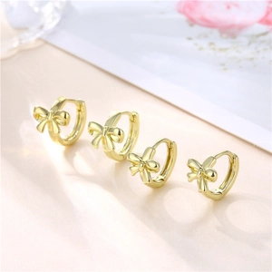 Polished 18K gold bow-shaped hoop earrings for women on an elegant neutral background