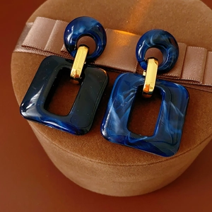 Detail of blue marble resin square earring resting on a luxury brown velvet jewelry box