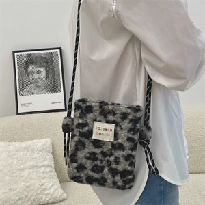 Detail of plush leopard print crossbody bag with woven rope strap on white shirt