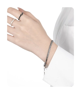 Close-up of S925 silver woven snake chain bracelet and wavy rings worn by model