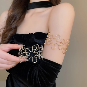 Detail of hollowed flower metal arm cuffs in gold and silver finish on model
