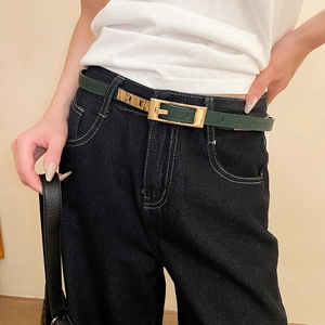 Close-up of slim dark green leather belt with a gold square buckle on denim jeans