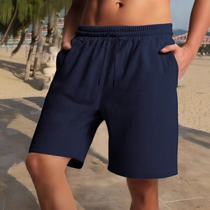 Men's navy blue textured drawstring casual shorts shown on a beach by a male model