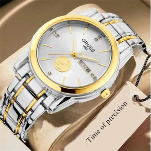 Detail view of gold-tone watch face featuring day-date window and nautical sailboat relief