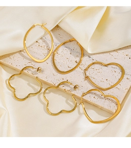 Detailed close-up of golden stainless steel chunky heart and oval hoop earrings on satin