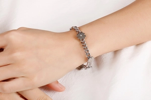 Macro view of silver stainless steel chain bracelet with lucky clover floral pendant