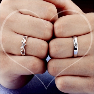 Detail of silver couple rings with wings design and heart shape hand gesture
