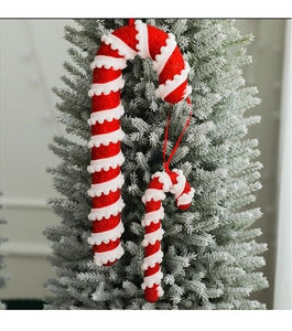 Detail of red and white striped Christmas candy canes hanging on a snowy Christmas tree