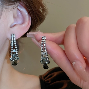 Detail of silver drop earrings with crystals shown on model and held by hand