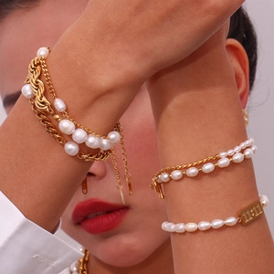 Detail of layered gold chain bracelets with white pearls and 11:11 plate on wrist