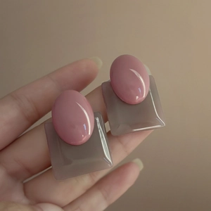 Handheld view of vintage oval pink and taupe geometric resin earrings for women