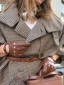 Detail of British style houndstooth wool coat with brown cutout leather gloves