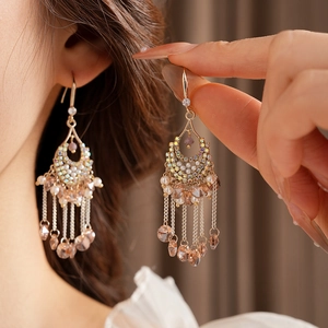 Close-up of vintage gold tassel earrings with colorful crystals and pearls on a model