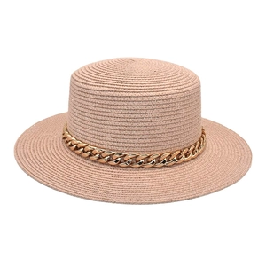 Détail de la texture d'un chapeau de paille rose avec chaîne en acrylique dorée