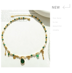 Detail of bohemian gold bead necklace with freshwater pearls and green gemstone pendant
