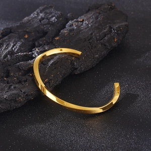 Macro detail of golden Mobius twist bangle showing metallic texture on dark stone