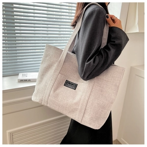 Detail shot of canvas tote bag texture with black fashion label and minimal design