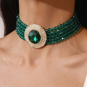 Close-up of vintage gold choker with green beads and large emerald-cut rhinestone center