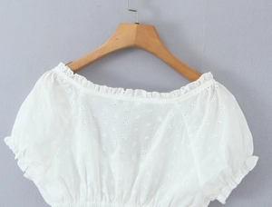 Dettaglio del crop top bianco in pizzo San Gallo con ricamo traforato e orlo elastico